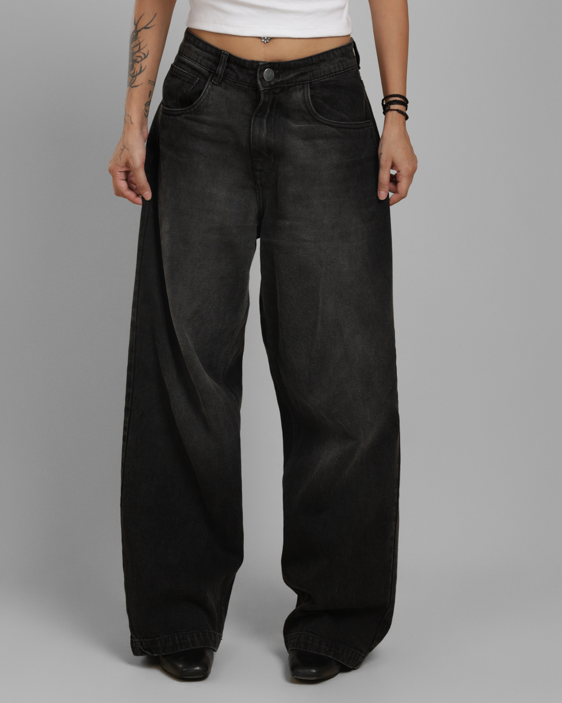 Person wearing black wide-leg jeans on a gray background