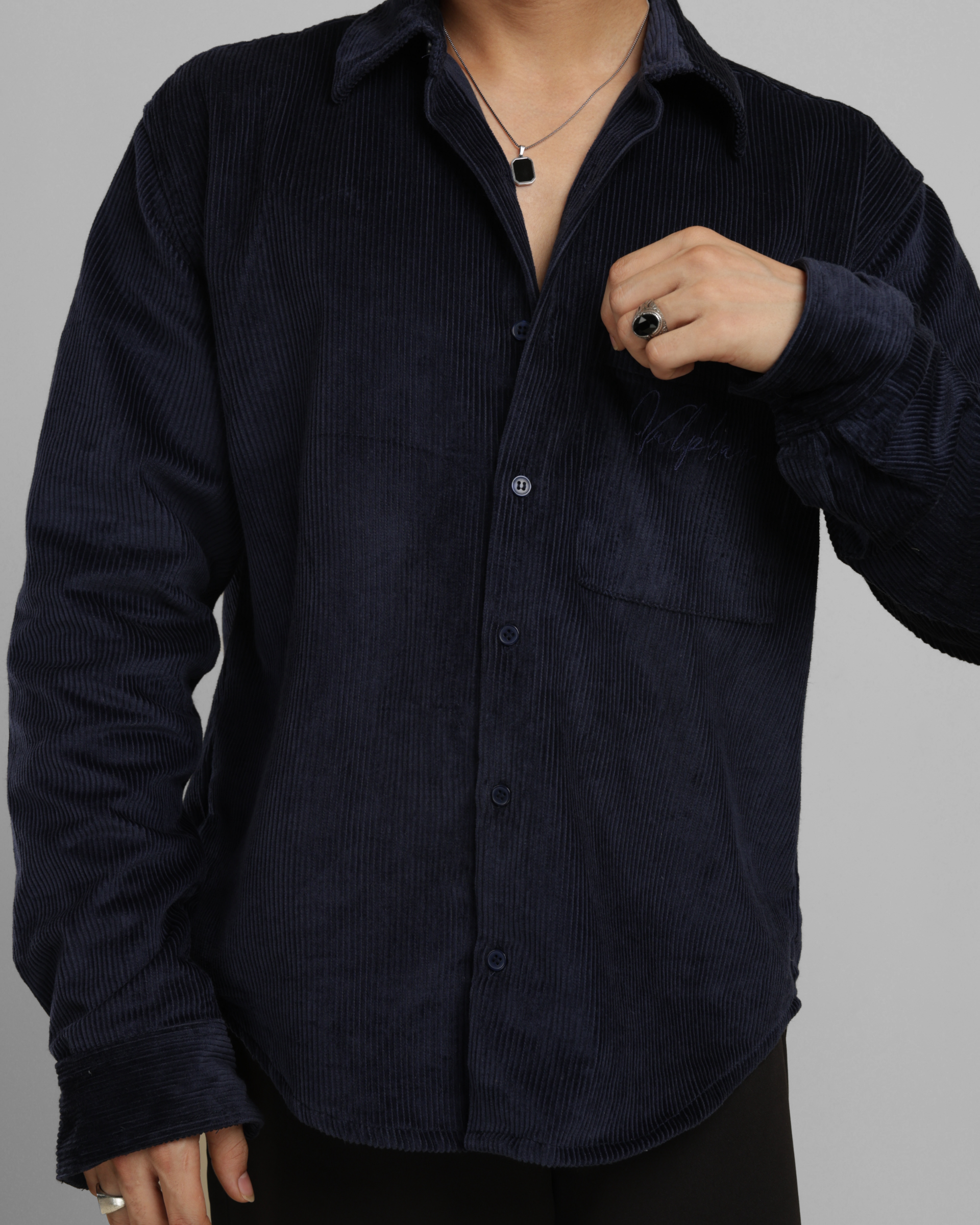 Person wearing a dark blue corduroy shirt against a gray background