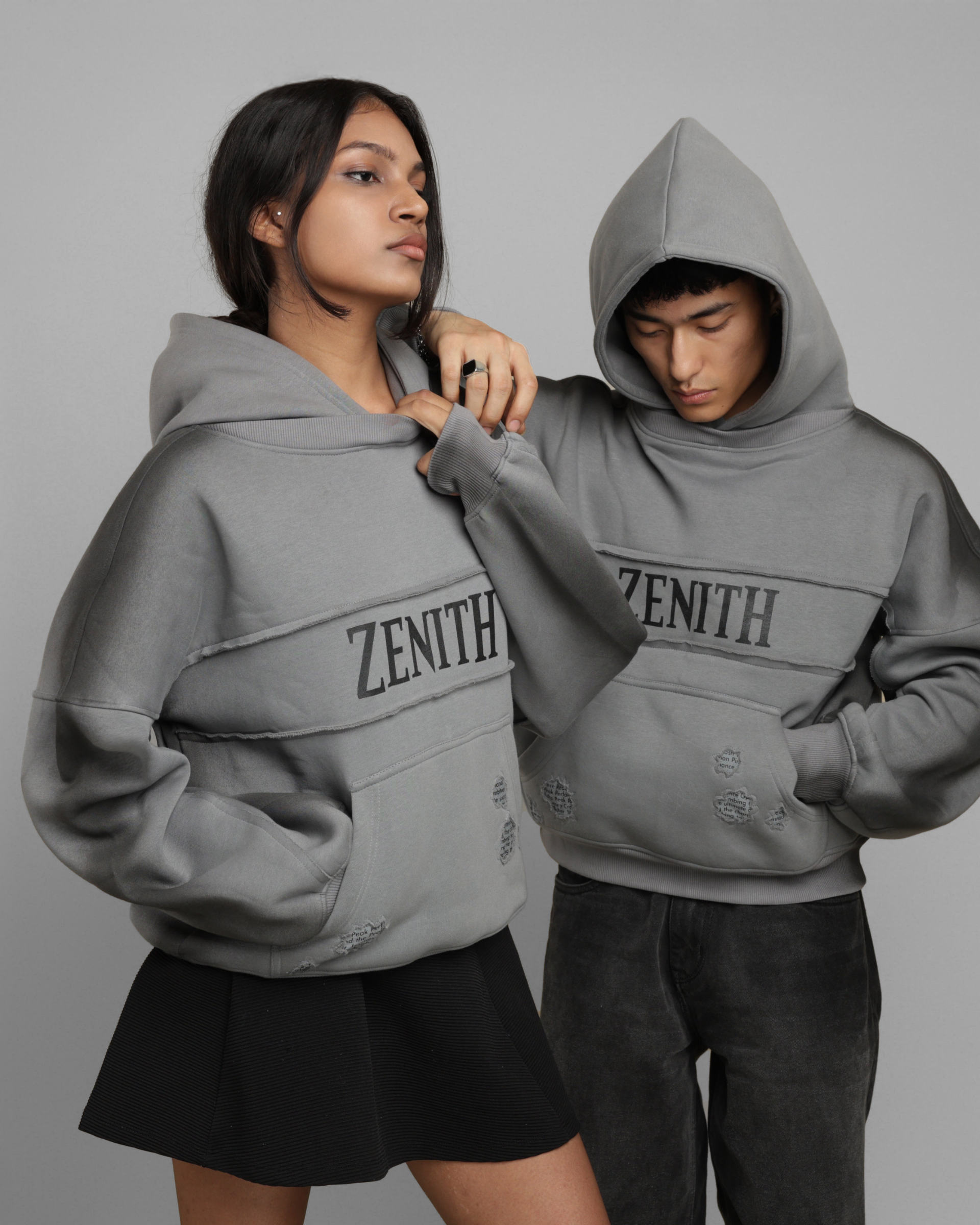 Two people wearing gray 'Zenith' hoodies against a plain background