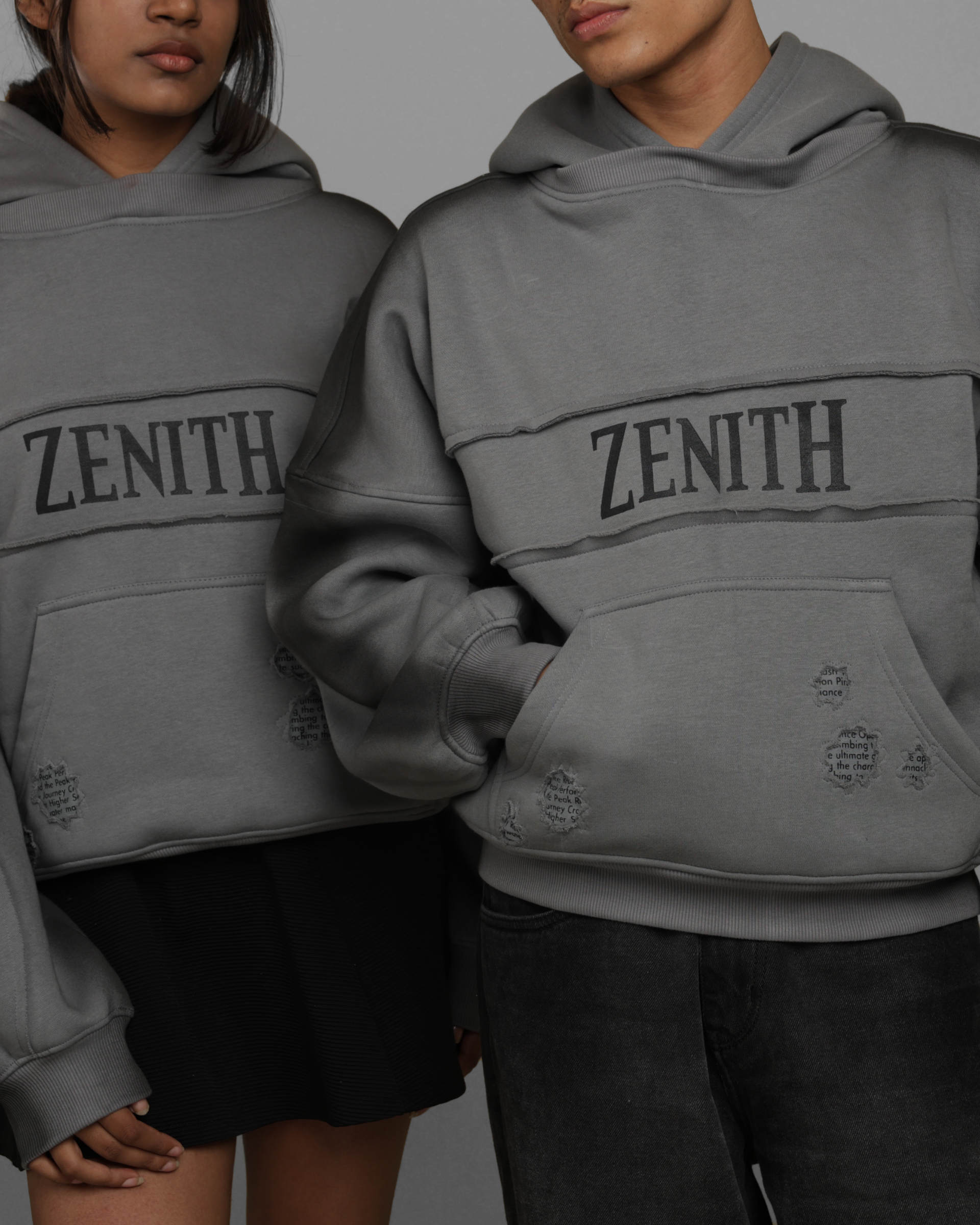 Two people wearing gray 'Zenith' hoodies against a gray background