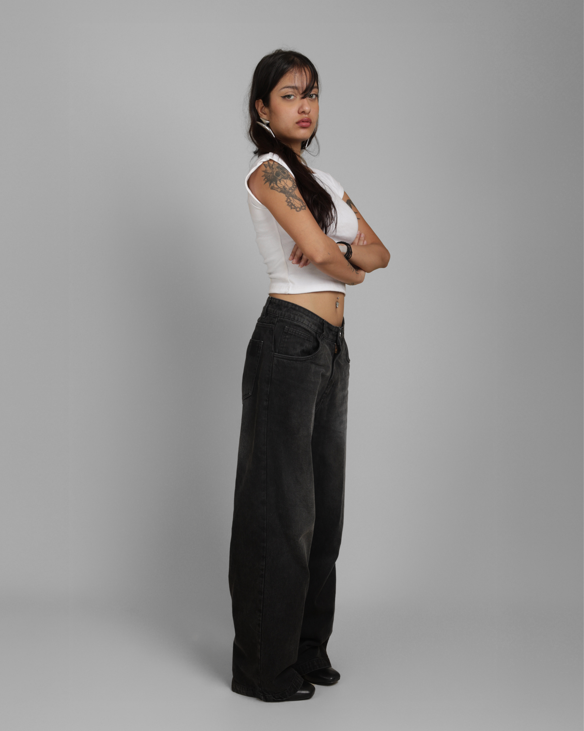 Person wearing a white sleeveless top and black pants on a gray background