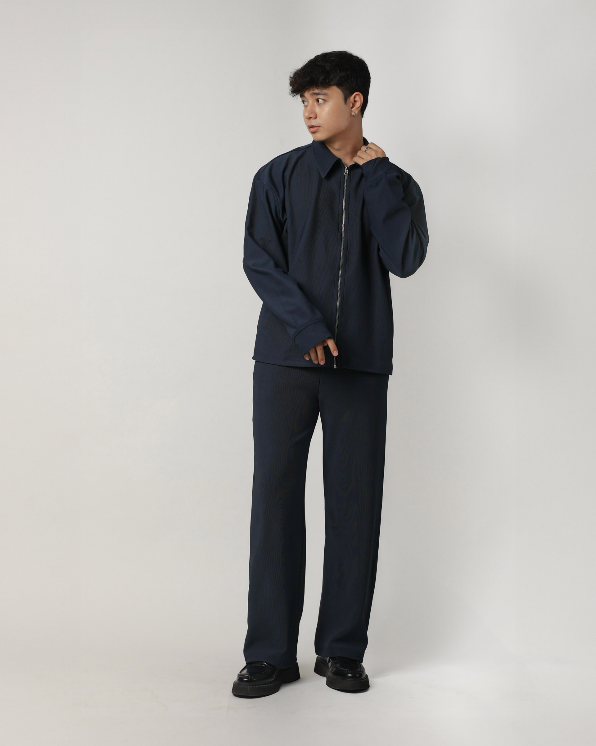 Person wearing a charcoal blue outfit on a white background