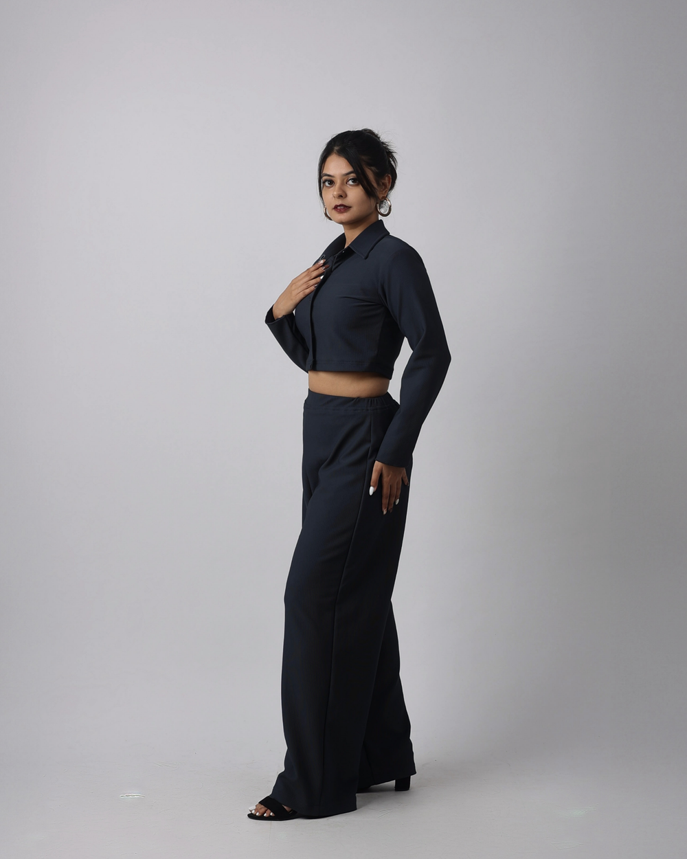 Woman wearing a charcoal blue outfit on a plain background