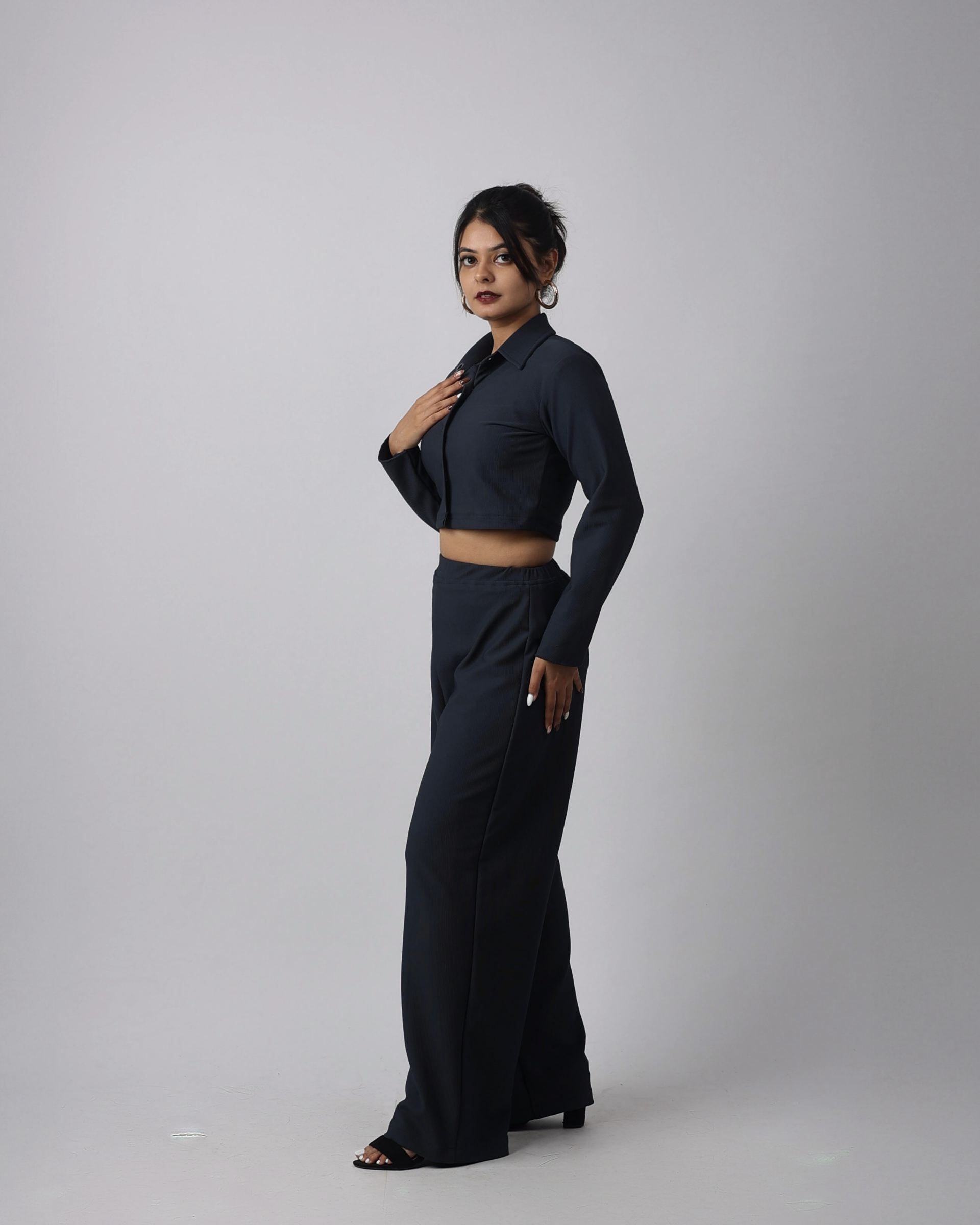 Woman wearing a charcoal blue outfit on a plain background