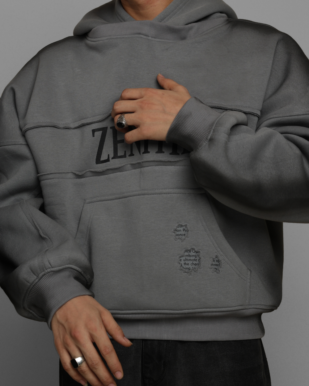 Person wearing a gray hoodie with 'Zenith' branding on a gray background