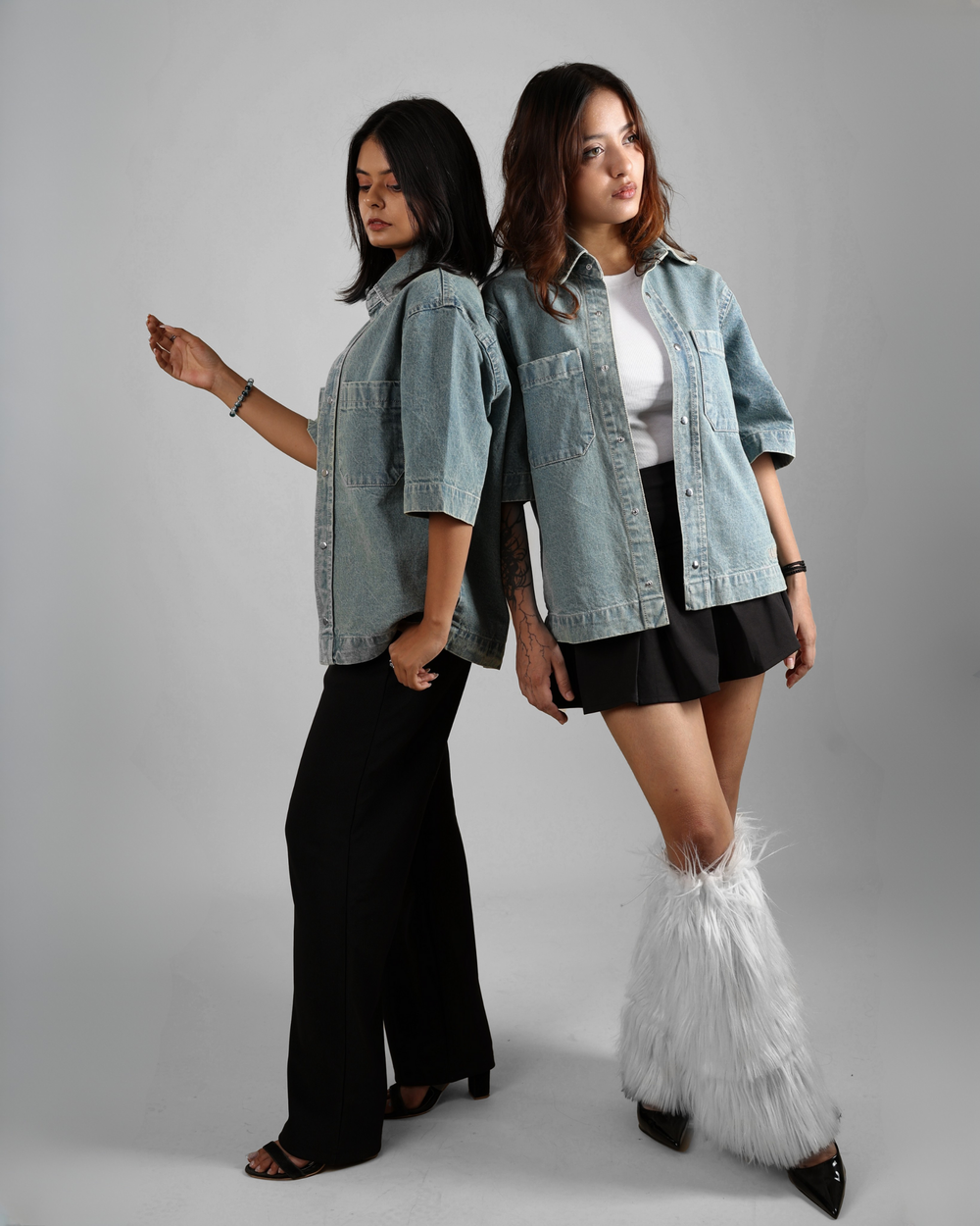 Two women wearing denim shirts on a gray background