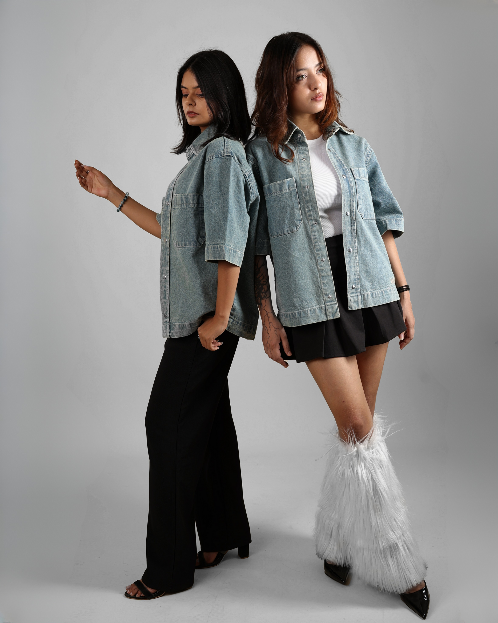 Two women wearing denim shirts on a gray background