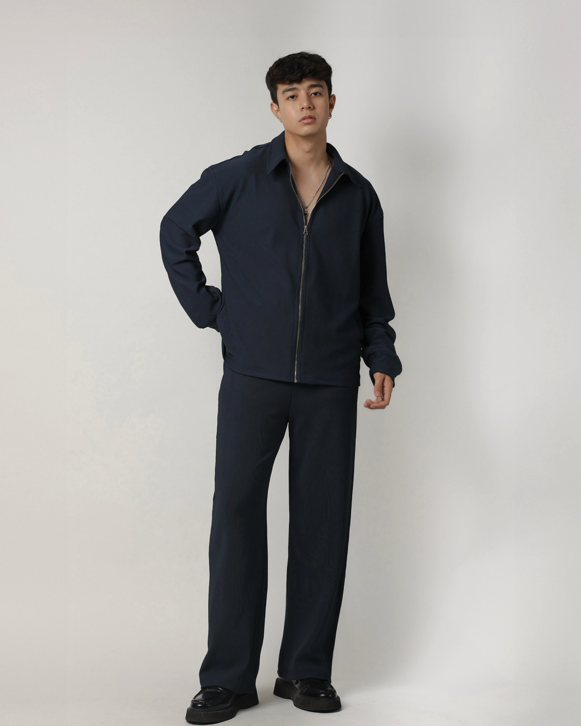 Man wearing a charcoal blue tracksuit against a white background
