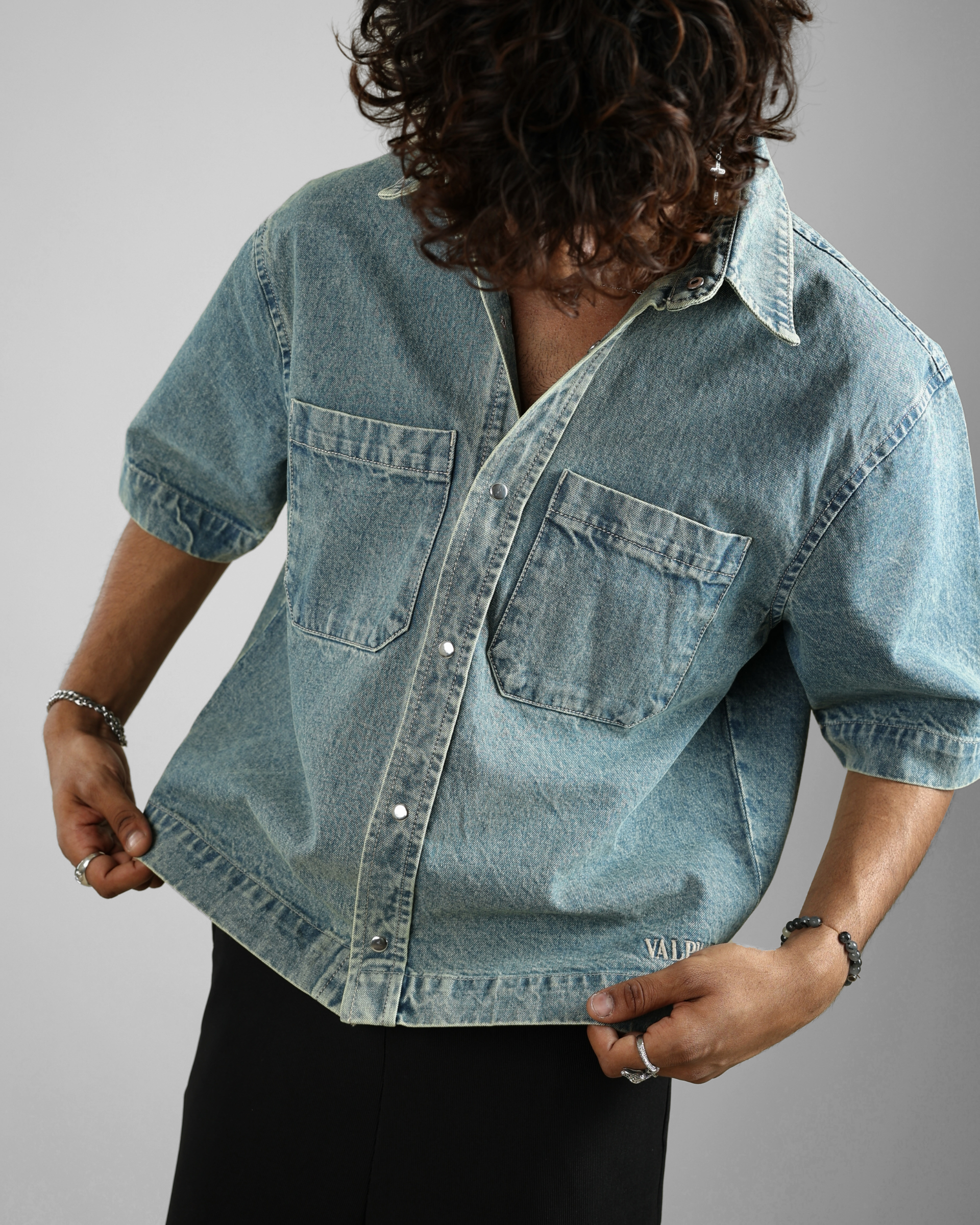 Person wearing a light blue denim shirt against a gray background