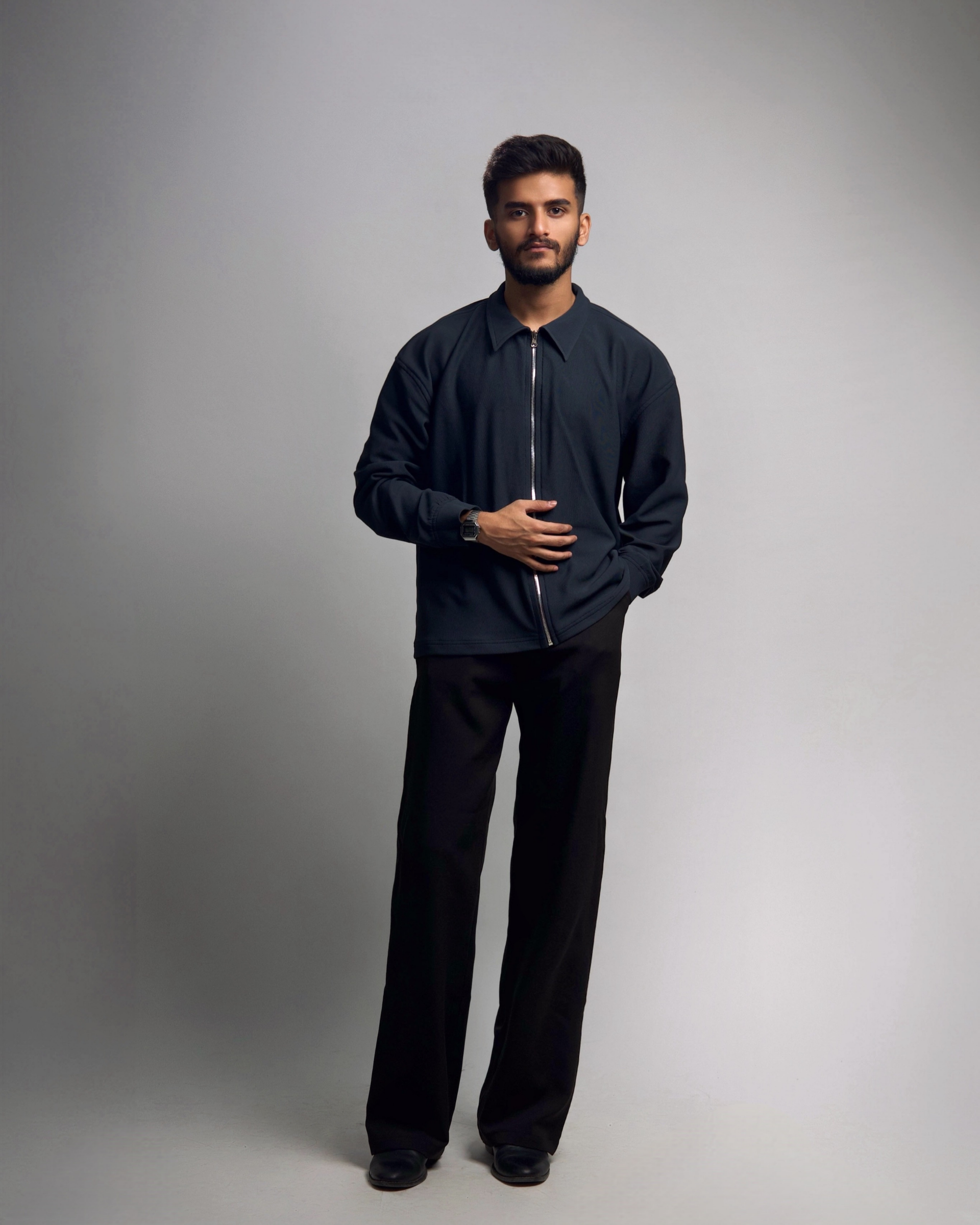 Man wearing a black outfit against a gray background