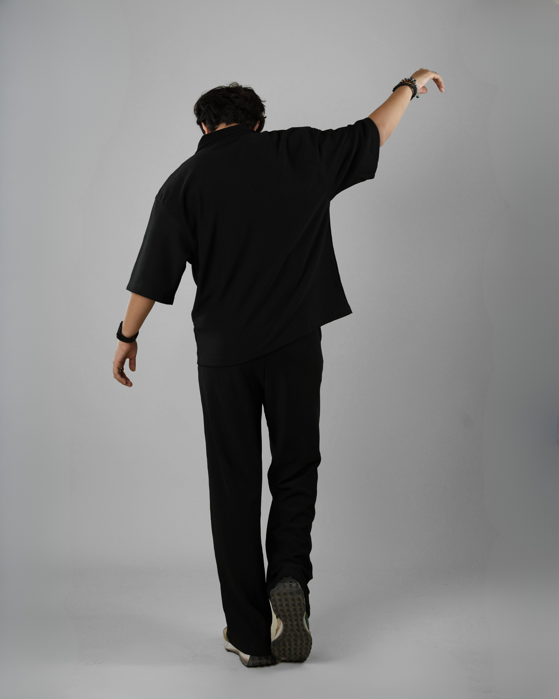 Person wearing a black outfit on a gray background