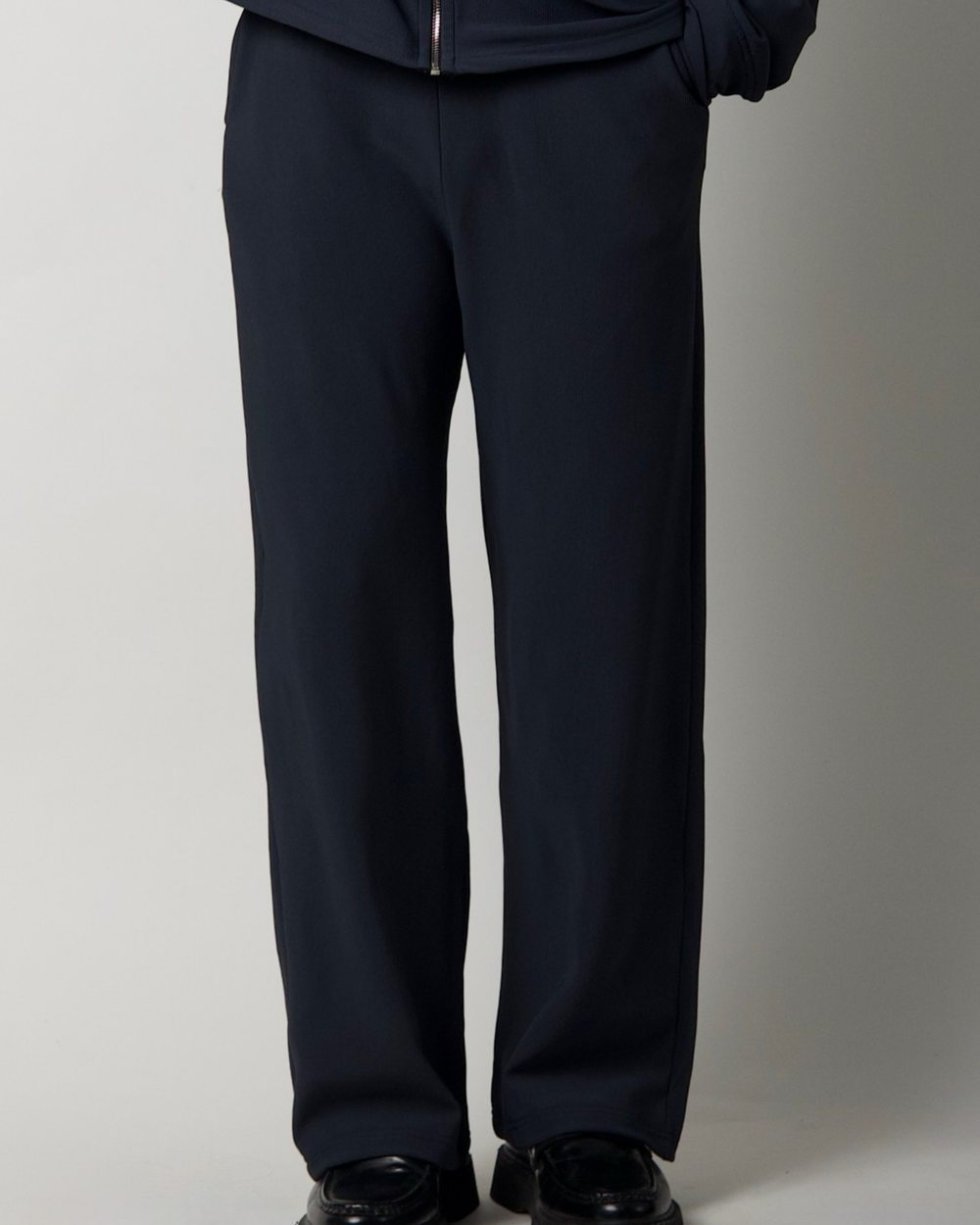 charcoal blue pants worn by a person on a plain background