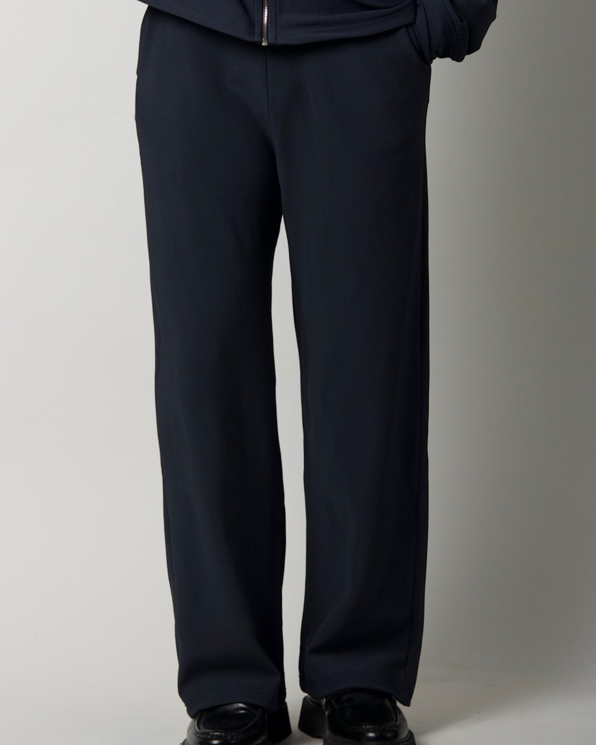 charcoal blue pants worn by a person on a plain background
