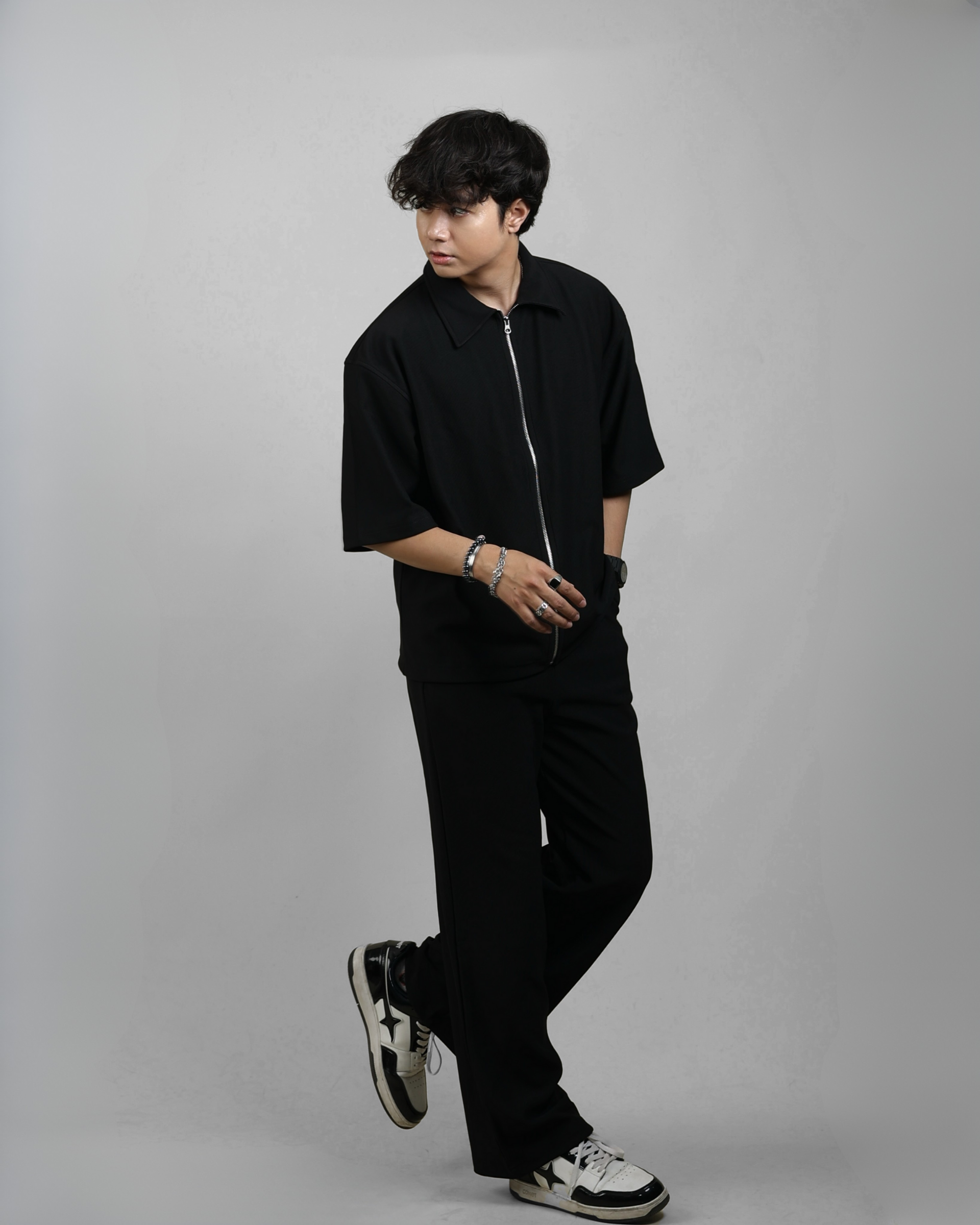Person wearing a black outfit with white sneakers on a gray background
