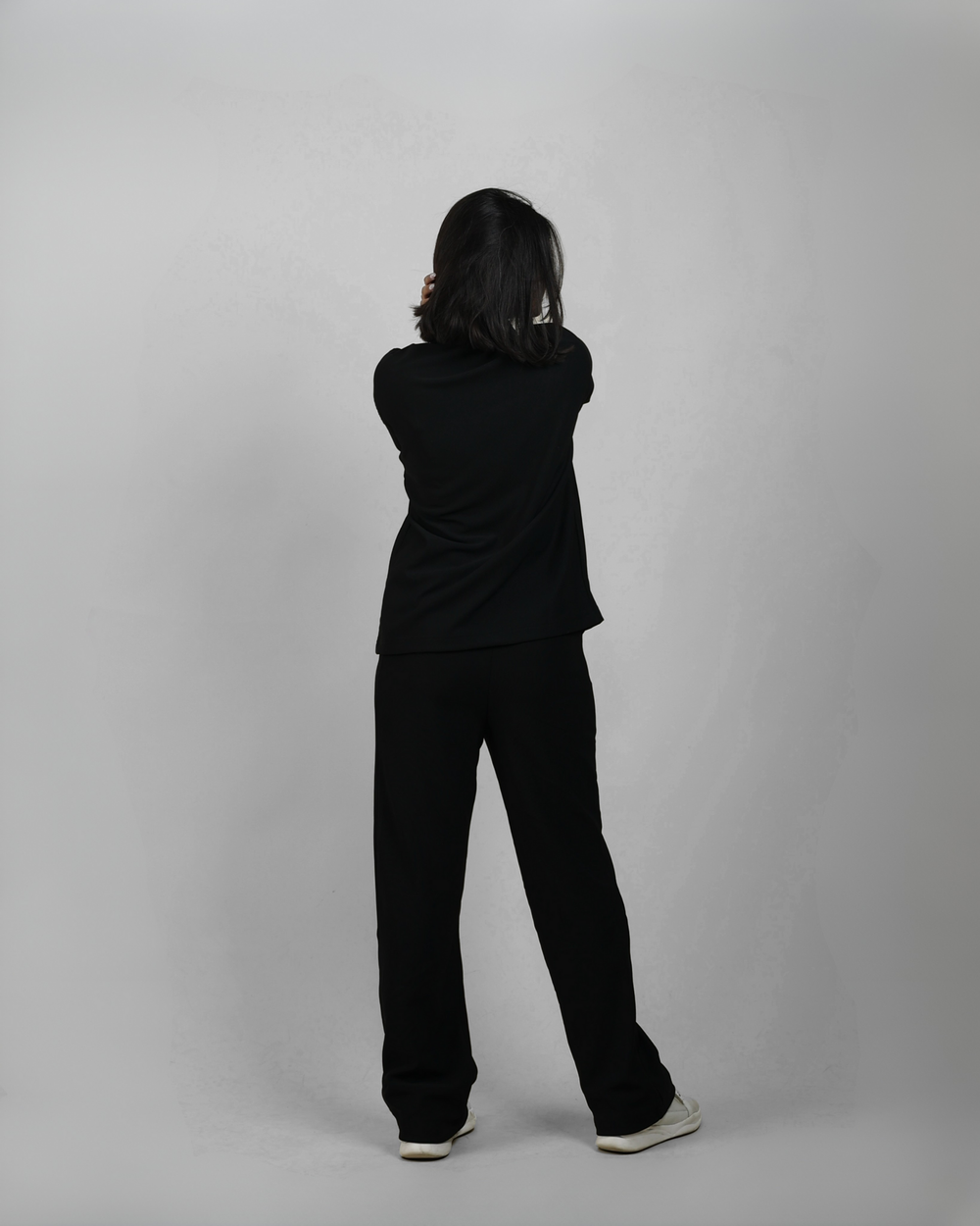 Person wearing a black outfit standing against a plain background