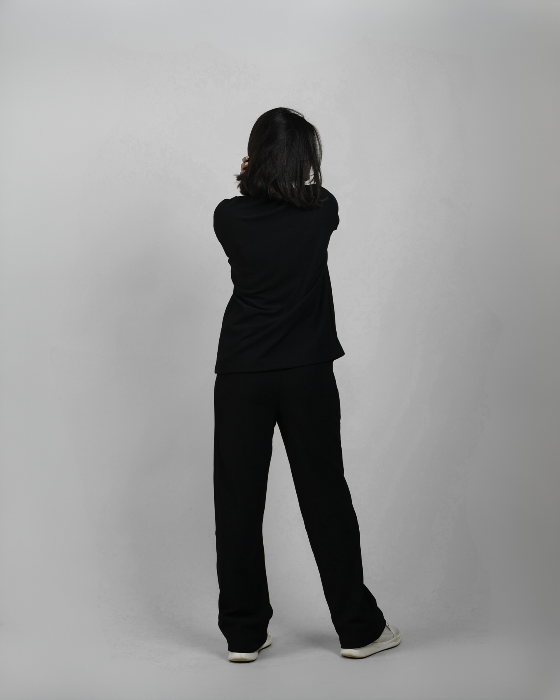 Person wearing a black outfit standing against a plain background