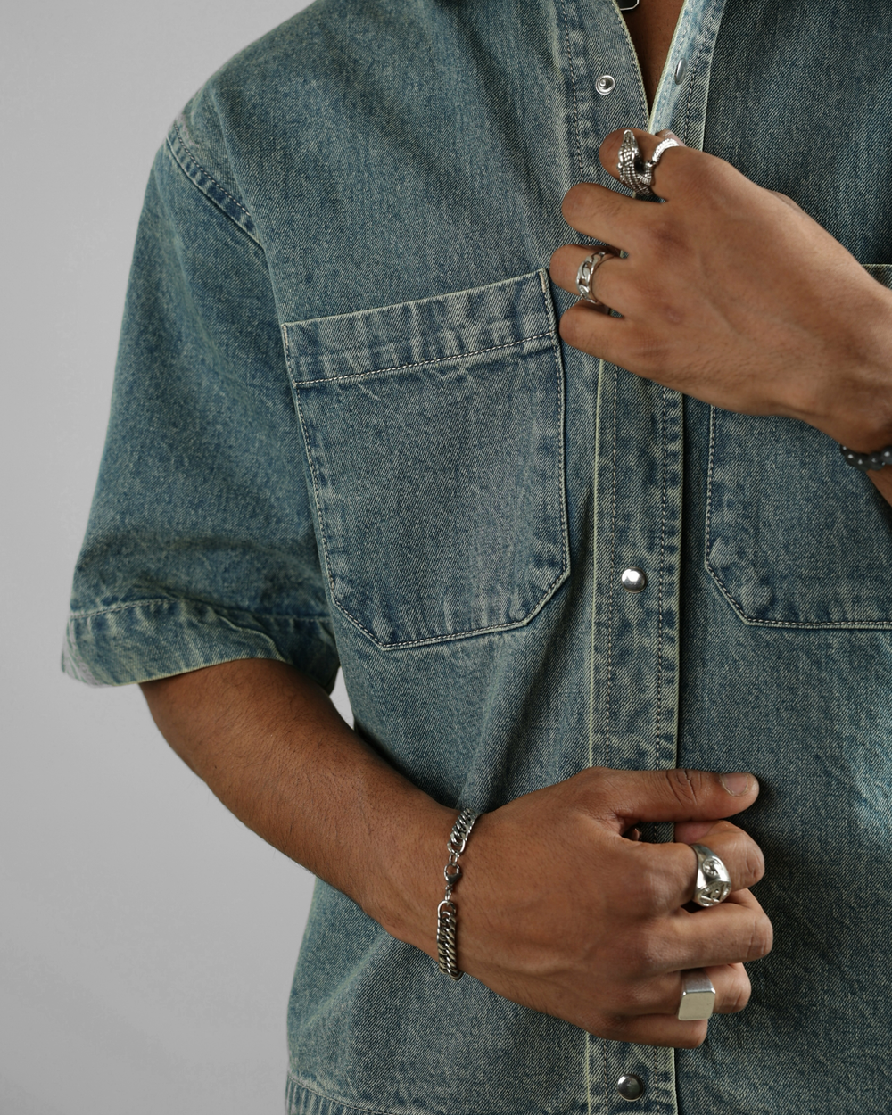 Person wearing a denim shirt with a focus on the shirt and hands.