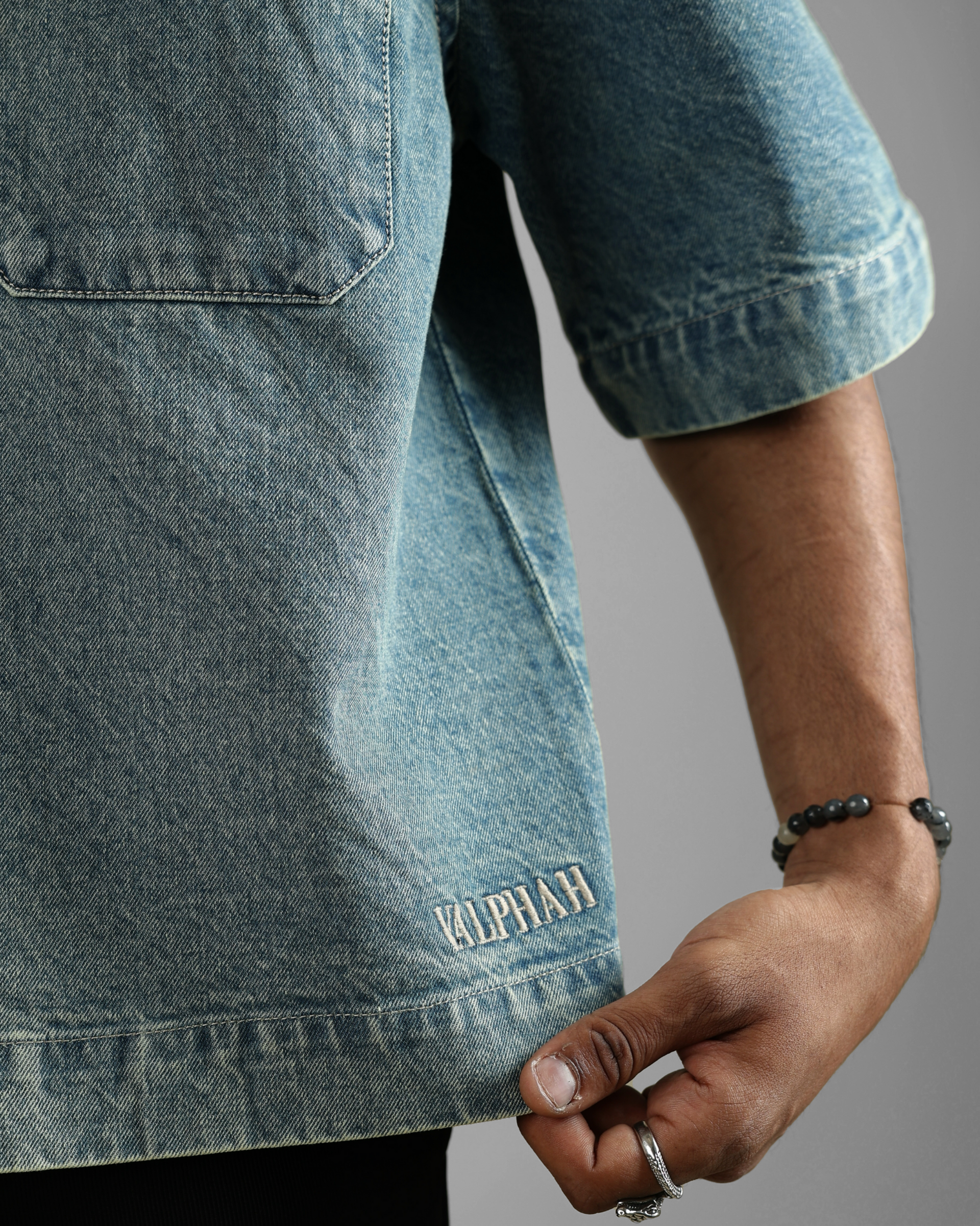 Close-up of a person wearing a denim shirt with 'valphah' branding on a gray background