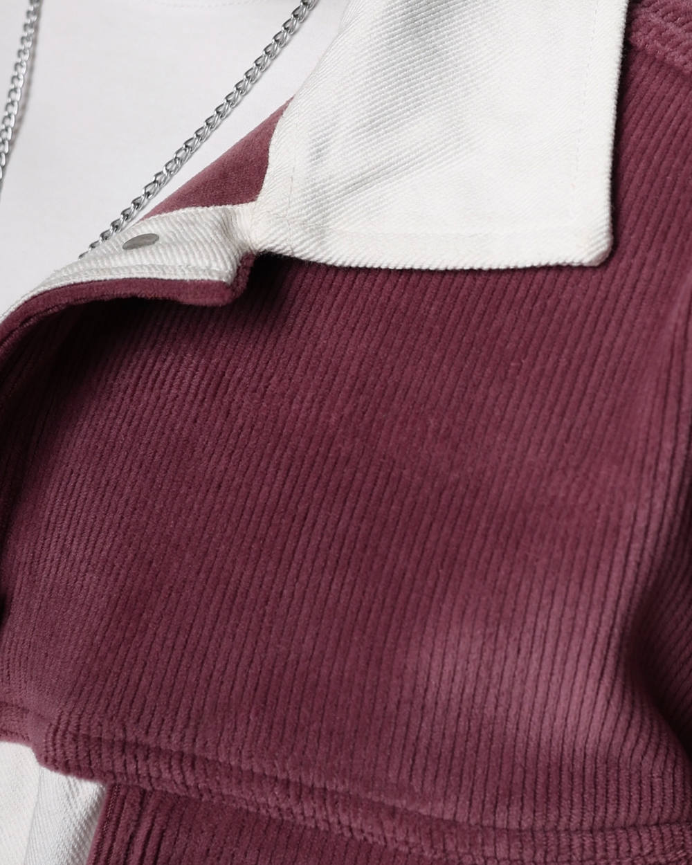 Close-up of a onion pink ribbed sweater with a white hood and zipper.