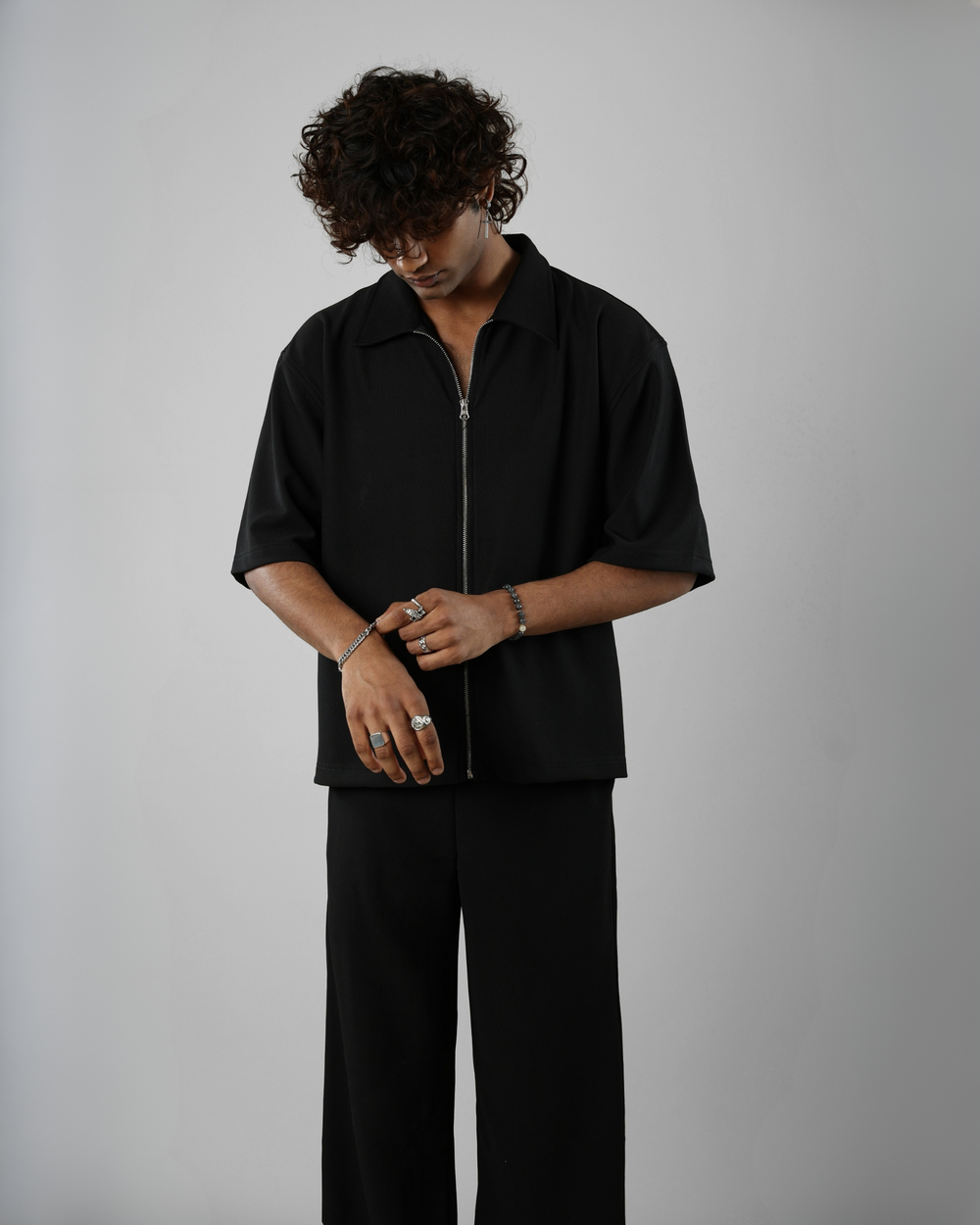 Person wearing a black outfit with a zipper on a gray background