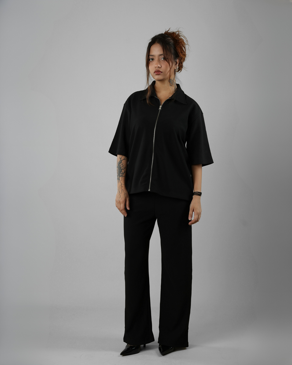 Person wearing a black outfit with a zipper on a gray background