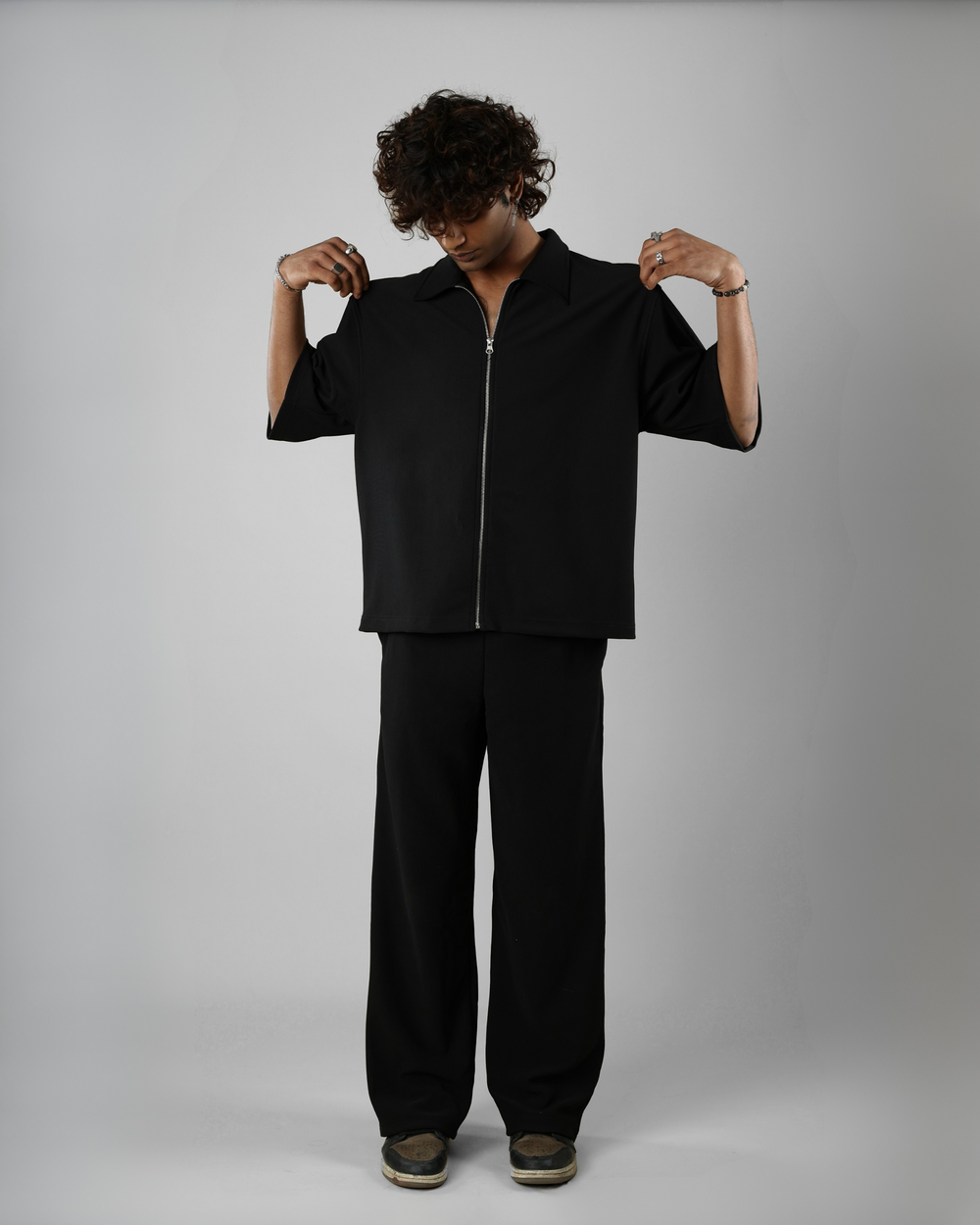 Person wearing a black outfit against a gray background