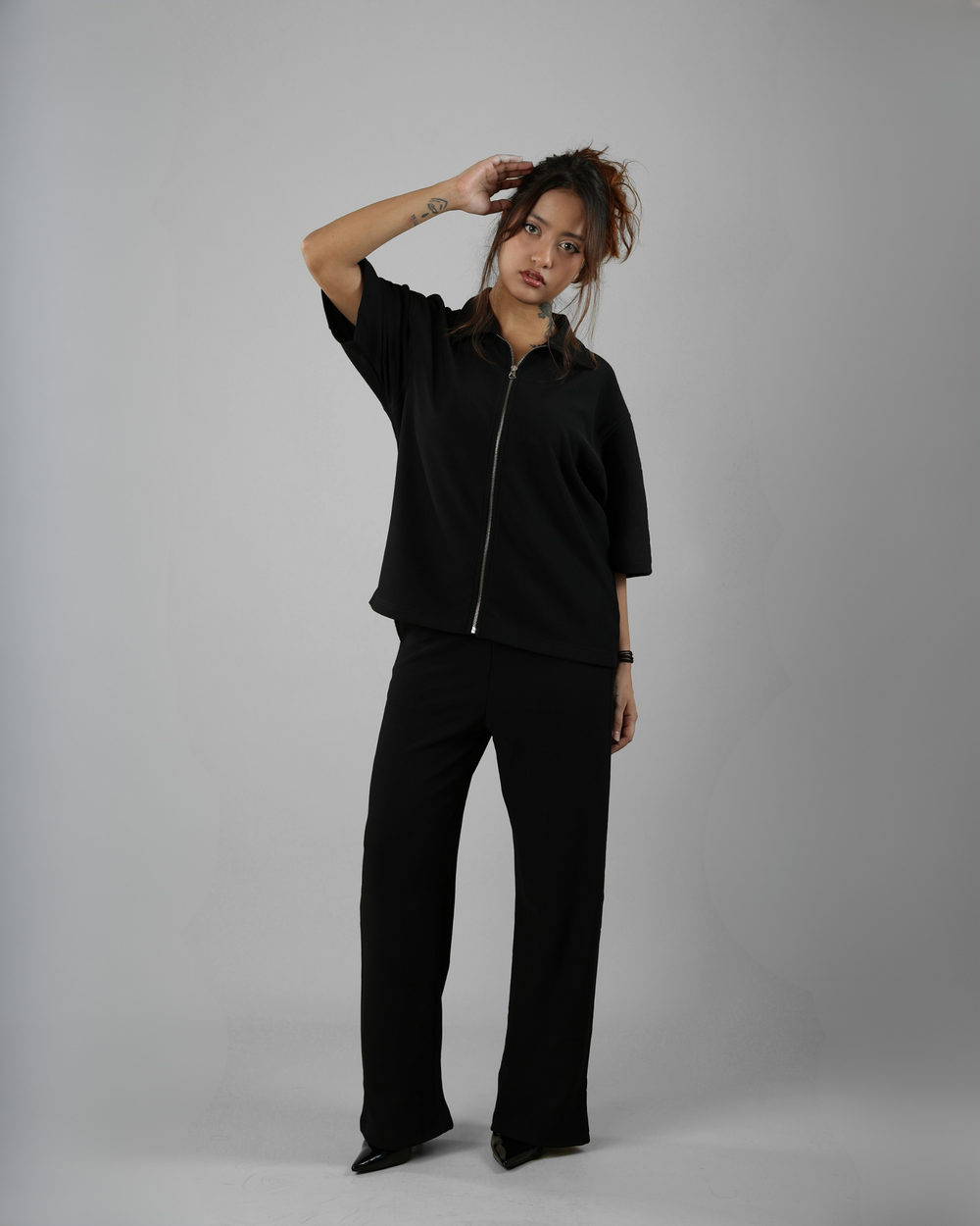 Person wearing a black outfit against a gray background