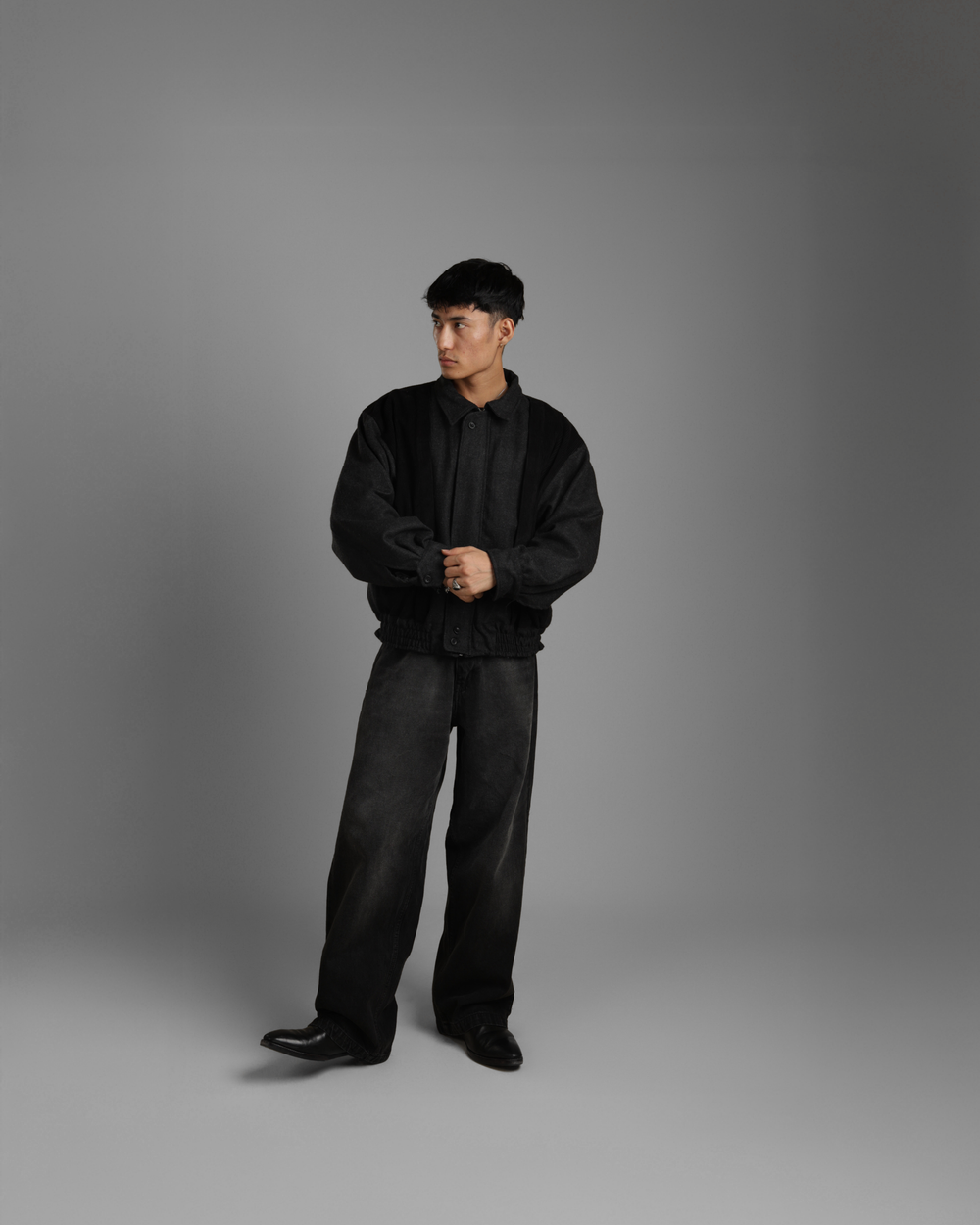 Person wearing a black outfit on a gray background