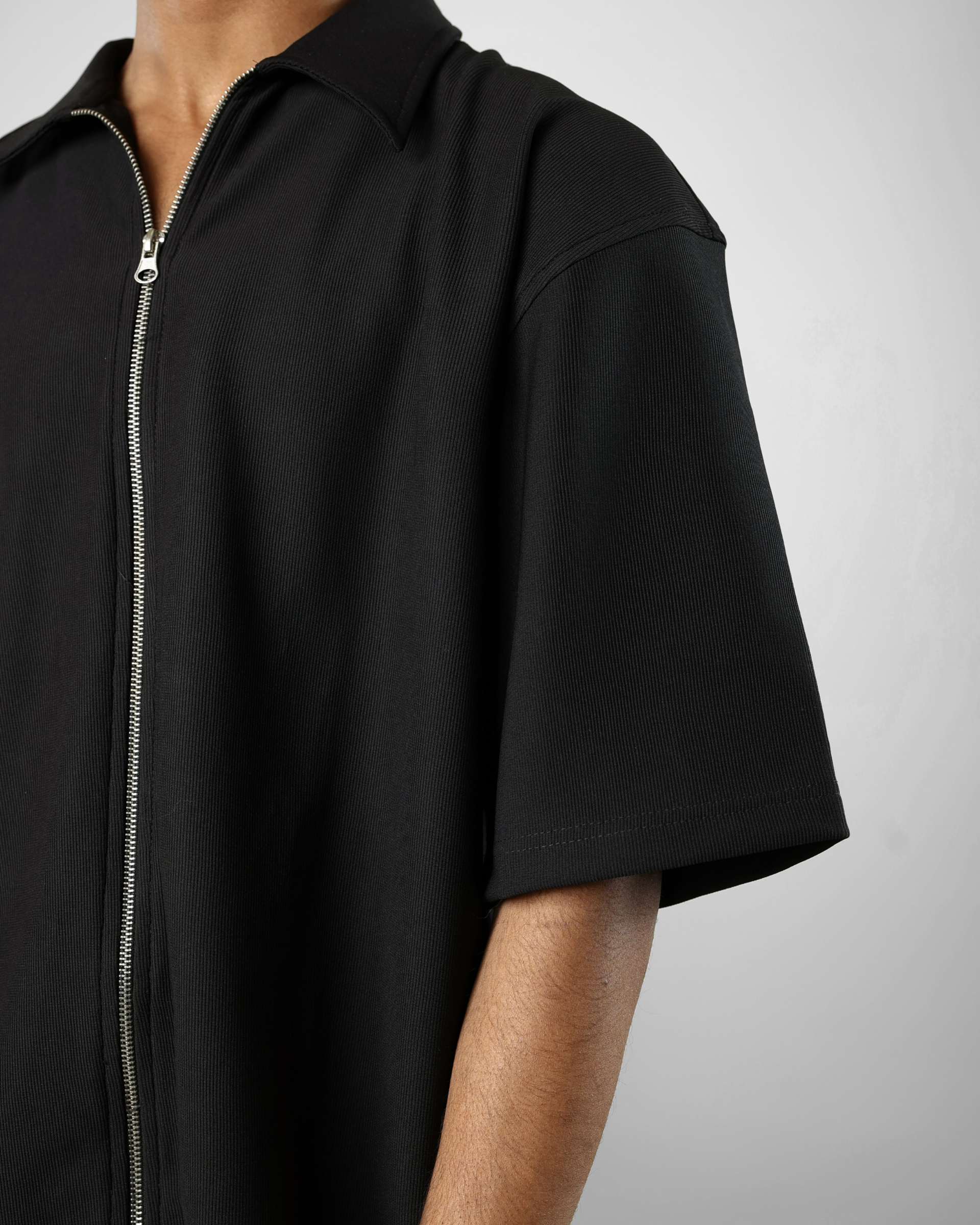 Black short-sleeve shirt with a zipper on a gray background