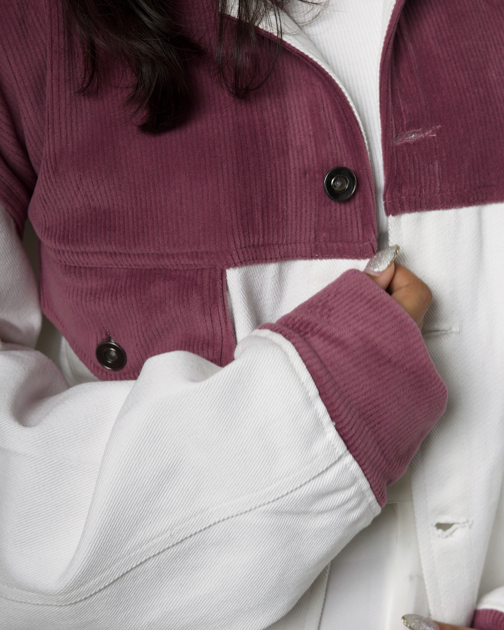 Close-up of a person wearing a white jacket with onion pink sleeve cuff.