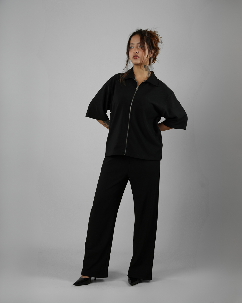 Person wearing a black outfit on a gray background