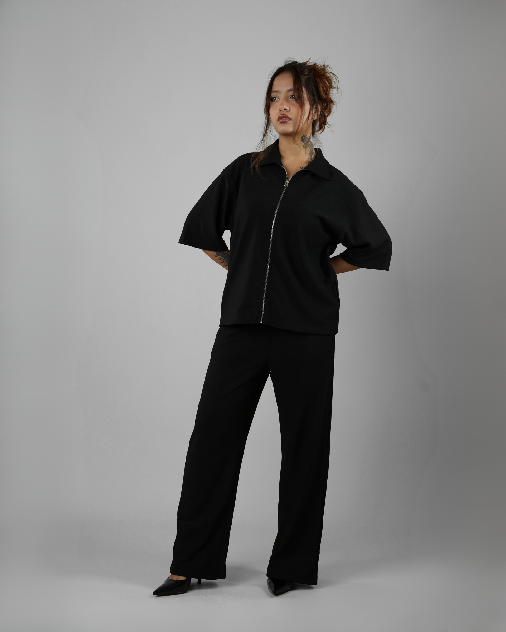 Person wearing a black outfit on a gray background