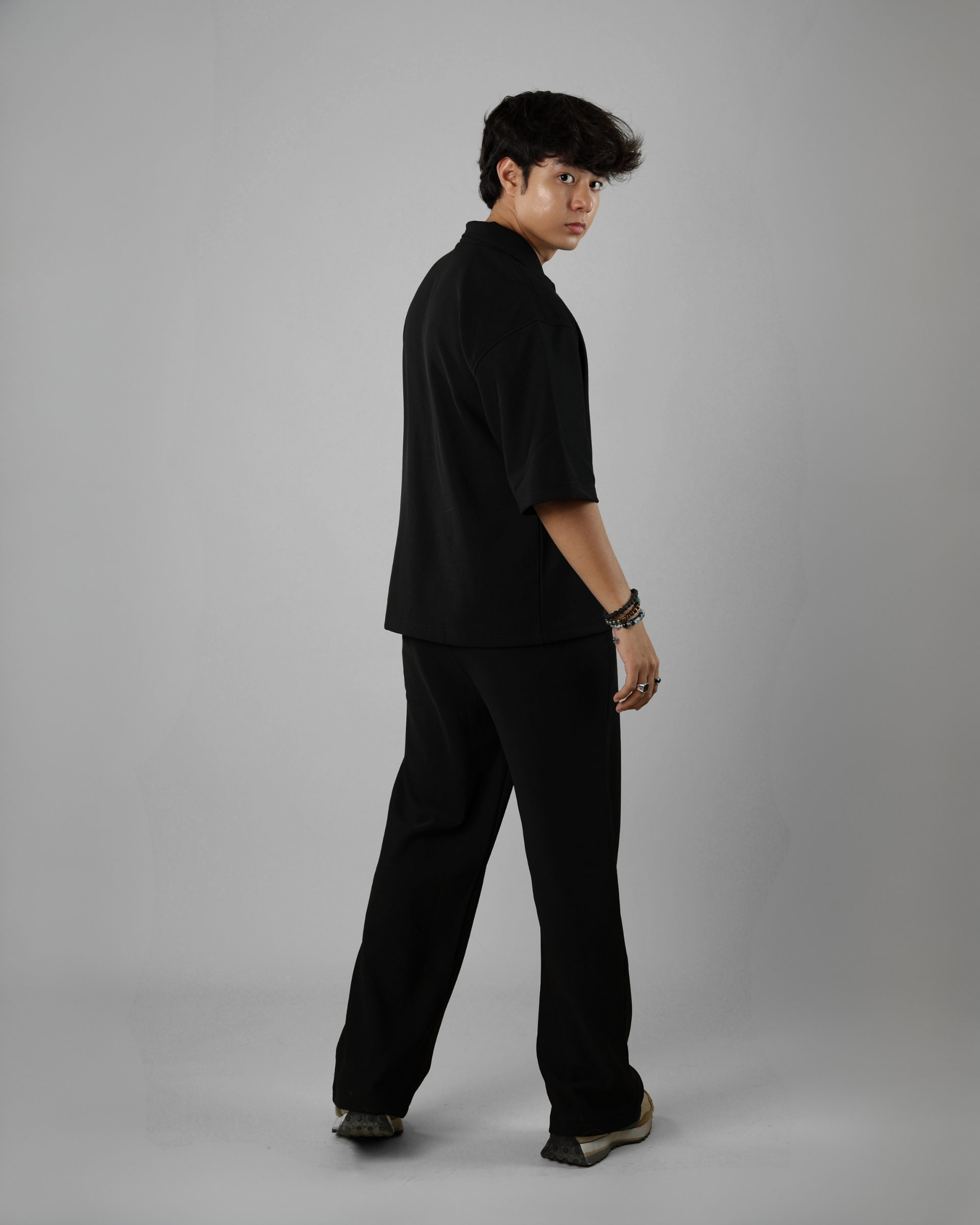 Person wearing a black outfit on a gray background