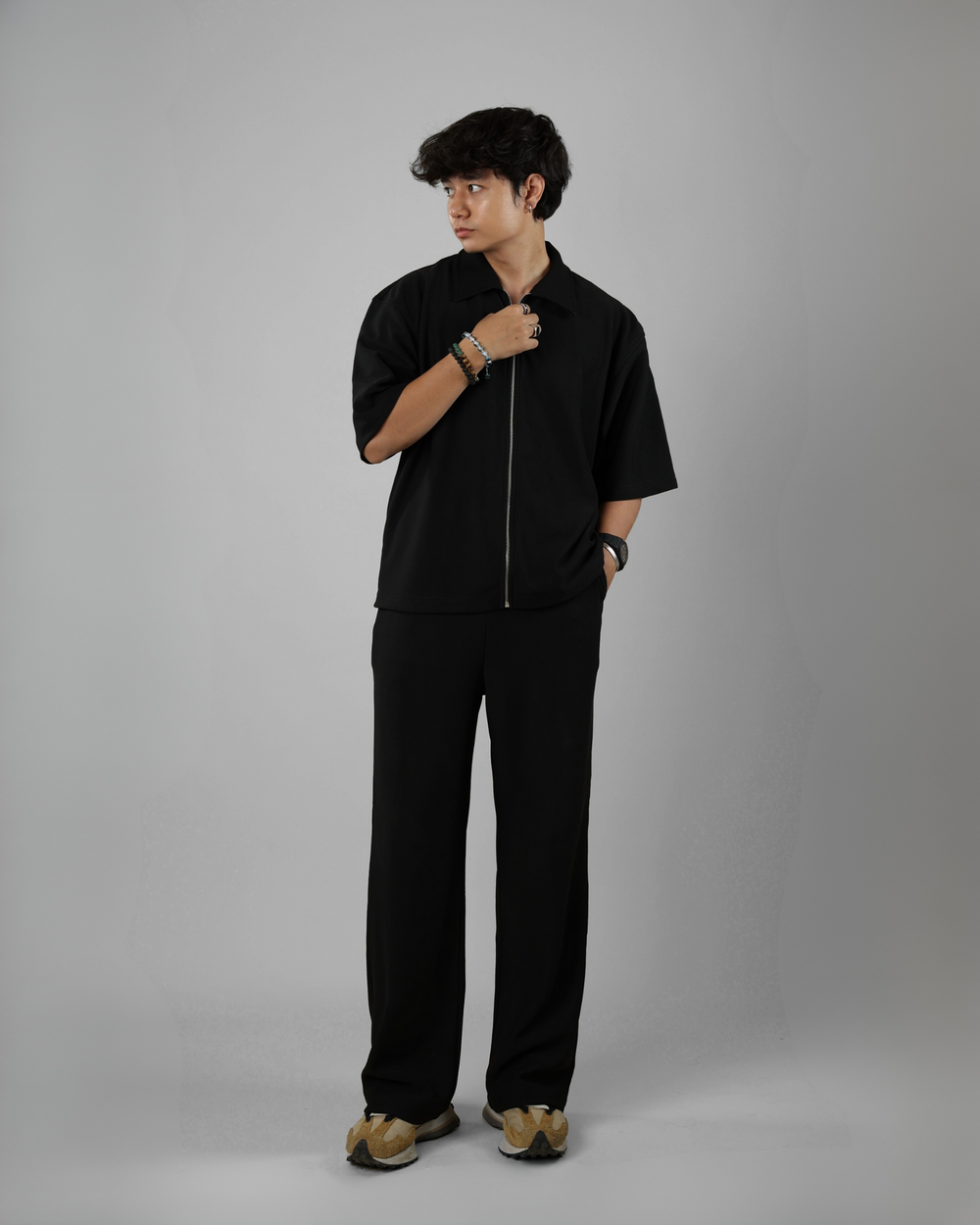 Person wearing a black outfit against a gray background