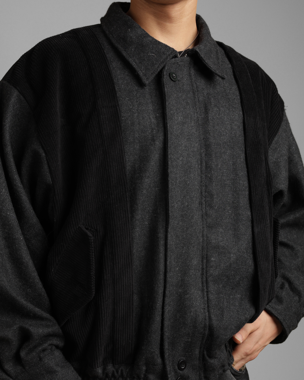 Dark gray coat worn by a person on a gray background
