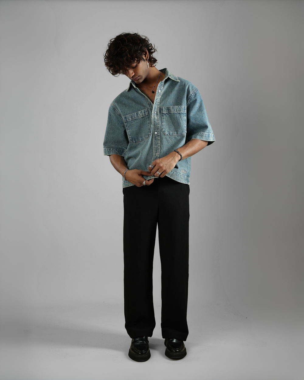 Person wearing a denim shirt and black pants on a gray background