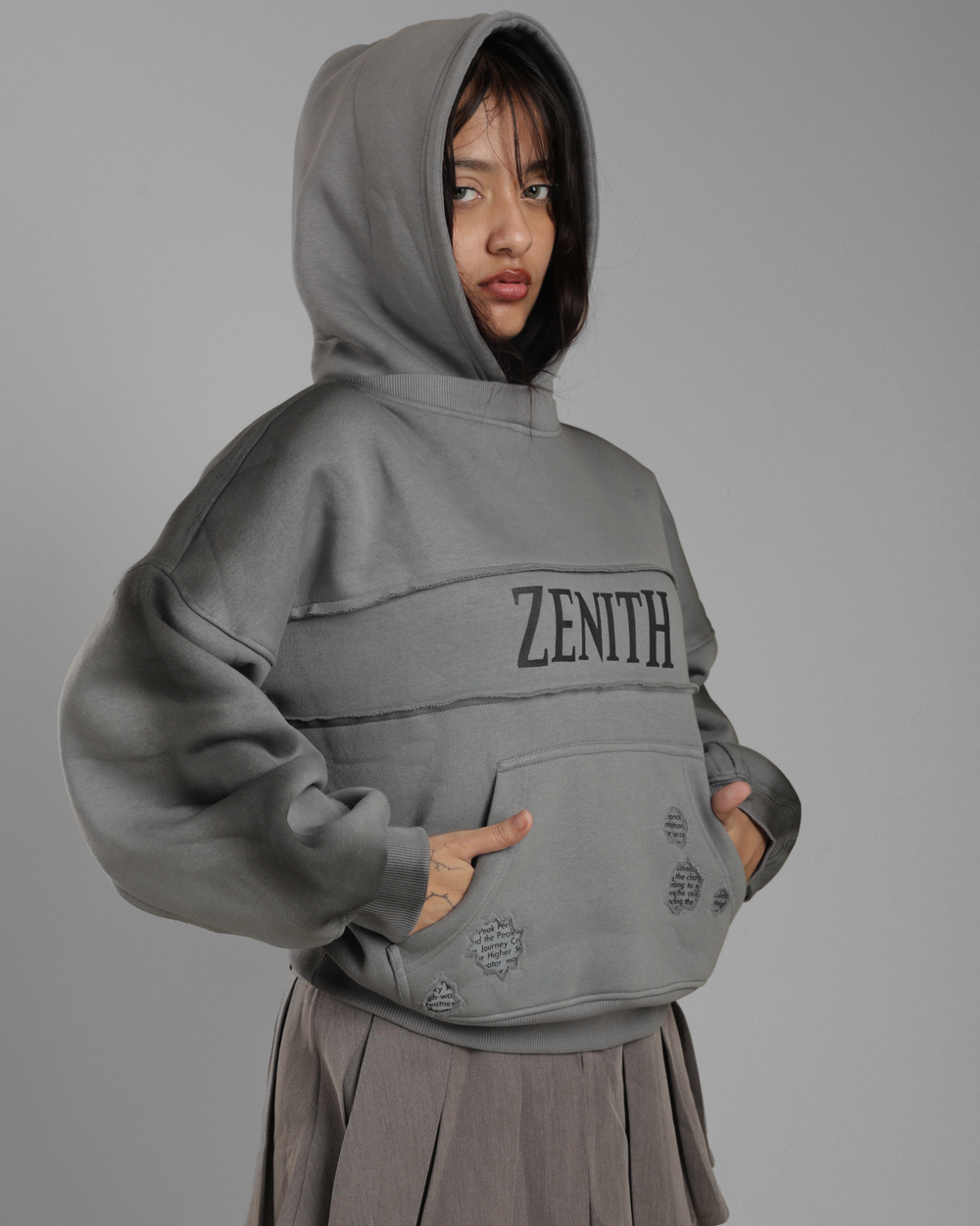 Person wearing a gray hoodie with 'Zenith' branding on a gray background