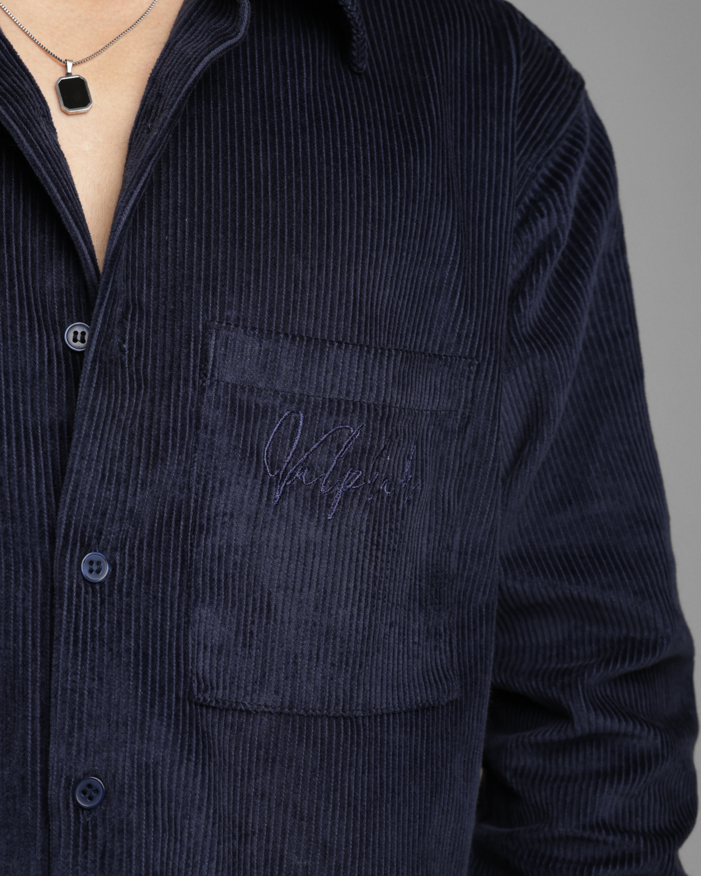 Navy corduroy shirt with a brand logo on a gray background