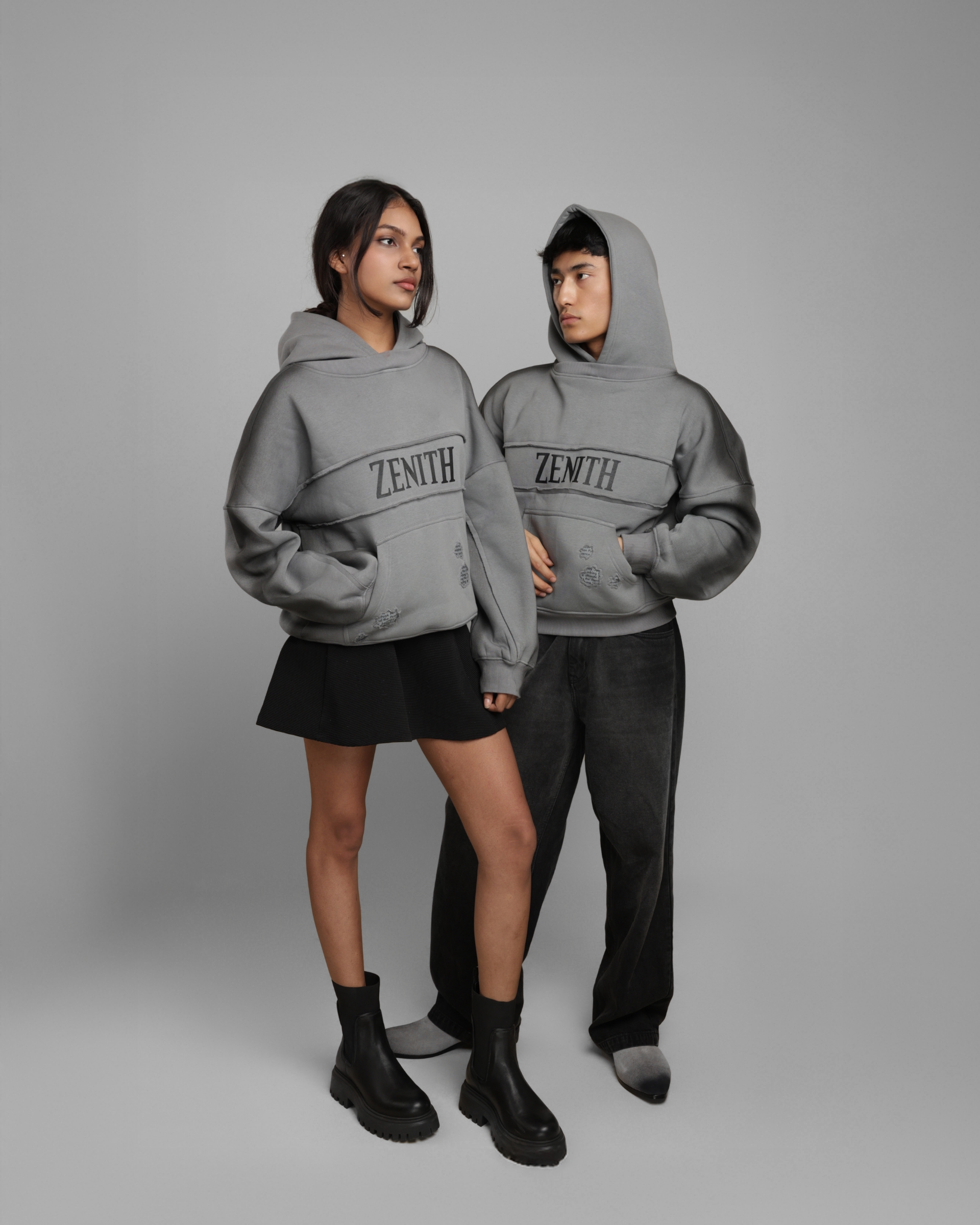 Two people wearing gray 'ZENITH' hoodies on a gray background