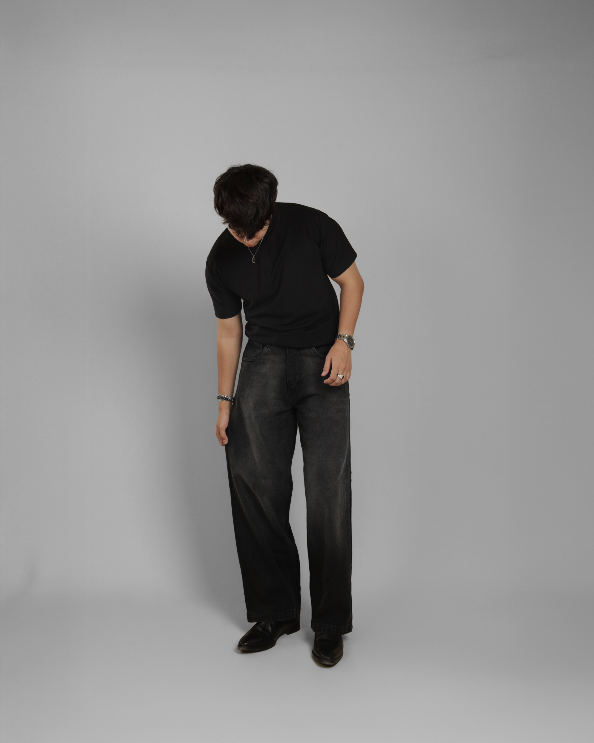 Person wearing a black outfit on a gray background