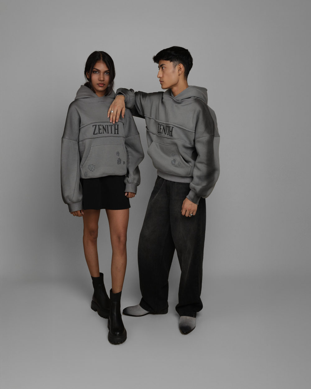 Two people wearing gray 'Zenith' hoodies on a plain background