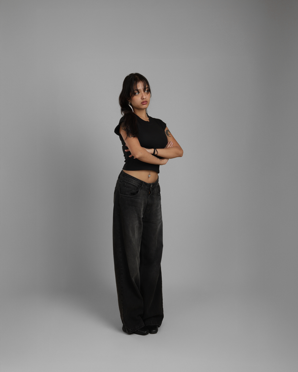 Person wearing a black outfit against a gray background