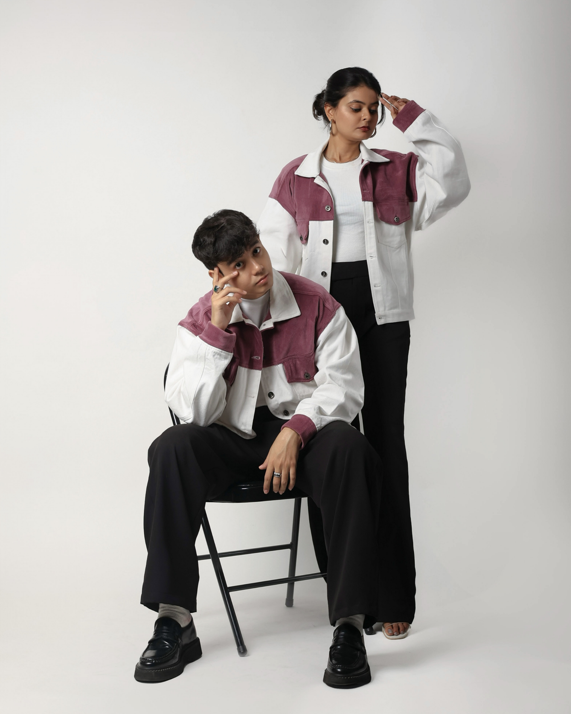 Two people wearing matching white and onion pink jackets on a plain background