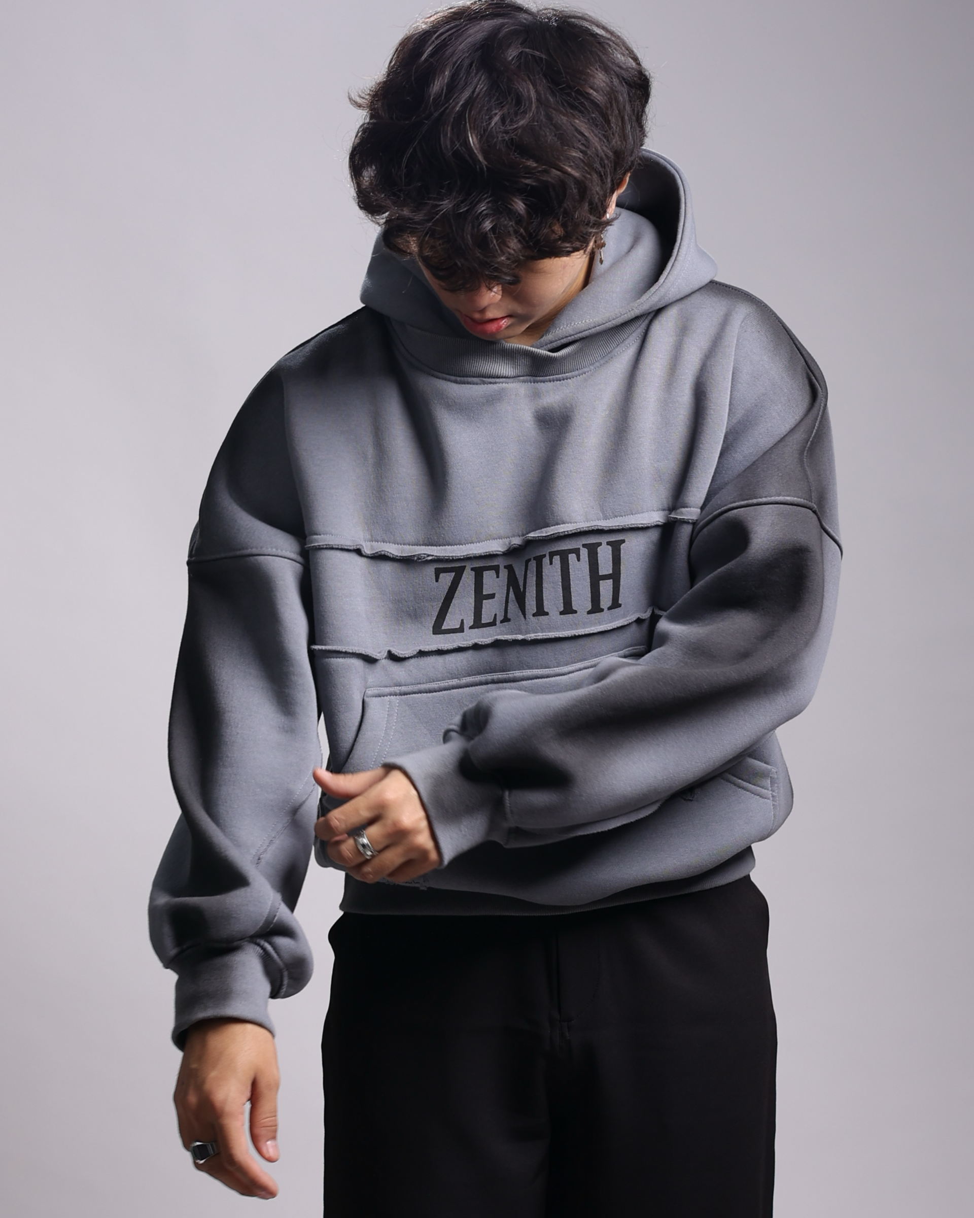 Person wearing a gray hoodie with 'ZENITH' branding on a plain background