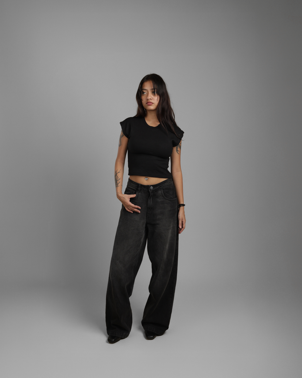 Person wearing a black outfit against a gray background