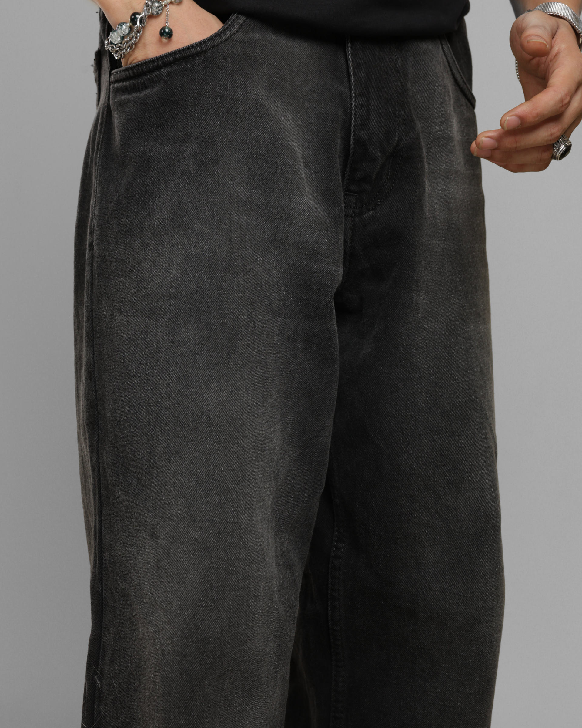 Dark black gray pants worn by a person on a plain background