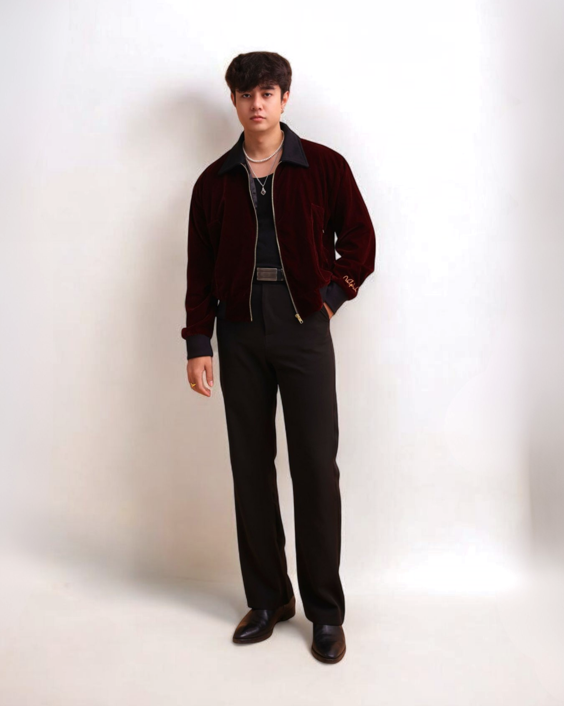 Man wearing a dark jacket and black pants on a white background
